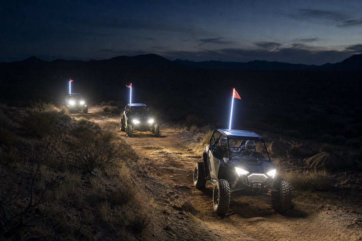 Three helmeted side-by-side crews staying together on a rocky sandy desert trail after dark